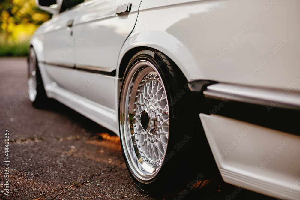 Classic shiny retro wheels on white car.