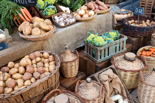 Vegetables and drinks for sell in vintage street market. Potatoes, carrots,green cauliflower,garlic, onions and cabbage in baskets.