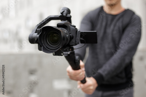 filmmaking, hobby and creativity concept - close up of modern dslr camera on 3-axis gimbal in male hands photo
