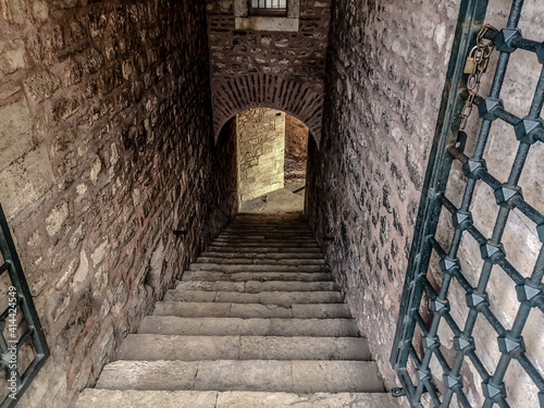 Exit from the garden of the Suleymaniye Mosque in Istanbul (Turkey). Ancient medieval corridor with stone walls, steps down and arched passage