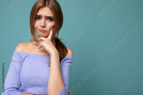 Photo portrait of moody thoughtful young nice beautiful blonde woman with sincere emotions wearing trendy blue crop top isolated over background with empty space and thinking with doubts