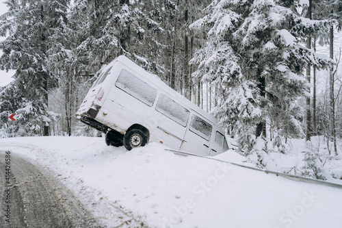 An accident on a winter snow-covered highway with a car skidding and falling into a ditch due to ice. Safety and poor driving on slippery and icy roads. Driving a car in extreme winter conditions