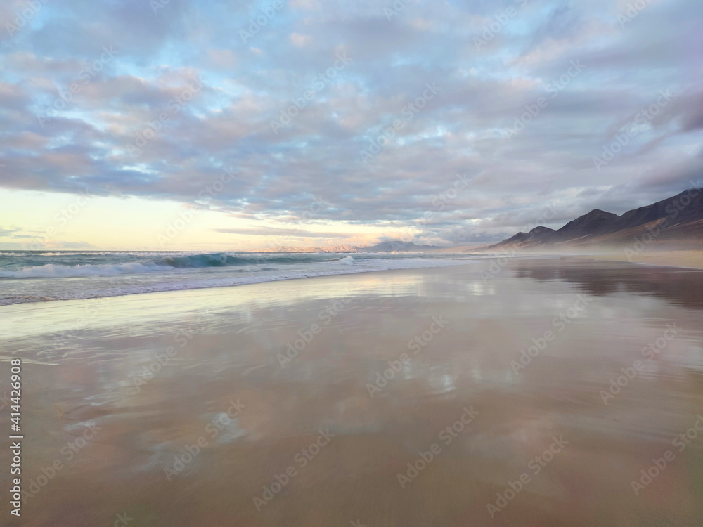 Cofete beach, beautiful cloudy sky reflect on the water. Fuerteventura, Canary Island, Spain.