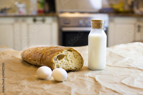 Basic  products for food and simple life. Ingredients for cooking. Bottle of milk, eggs and bread. Food for usual simple breakfast in white kitchen. Organic food. Farmer's food. Simple food.