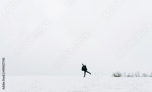 A happy female person jumps on the background of a winter snow-white landscape.The winter lifestyle.A small man against the background of a large nature.Minimal, stylish concept