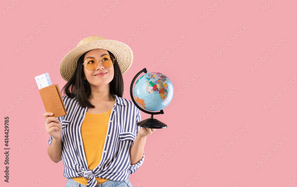 Fototapeta premium Asian woman holding passport with boarding pass and globe