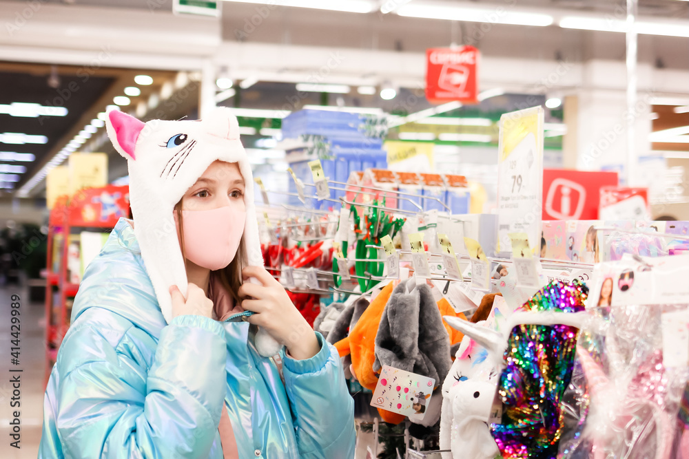 a cute teenage girl in protective medical mask choosing Christmas gifts in the store a cute teenage girl in protective medical mask choosing Christmas gifts in the store