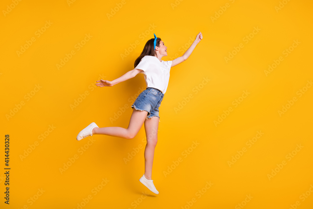 Full length body size photo of childish girl jumping high touching looking at blank space isolated on bright yellow color background