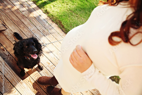 A pregnant couple with their black dog