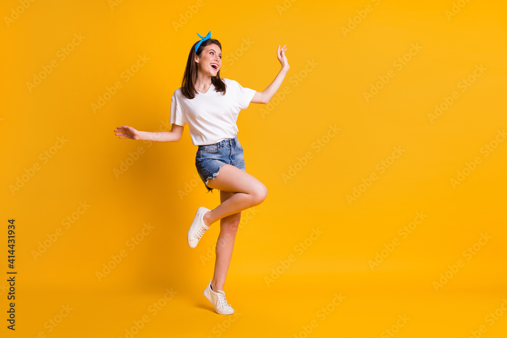 Full length body size view of skinny dreamy cheerful brown-haired girl jumping dancing isolated over bright yellow color background Full length body size view of skinny dreamy cheerful brown-haired girl jumping dancing isolated over bright yellow color background