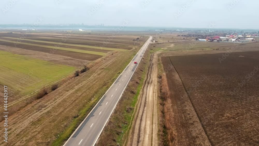 View of Highway from the drone at cloudy weather, fields on the both sides of the road with few cars, city and village in the distance, Moldova View of Highway from the drone at cloudy weather, fields on the both sides of the road with few cars, city and village in the distance, Moldova