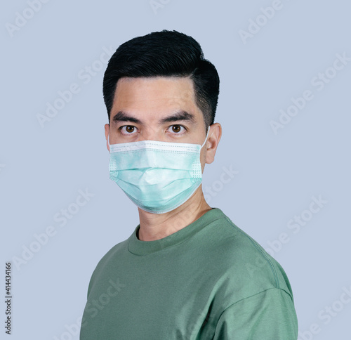 Stressful COVID-19 Coronavirus portrait handsome young asian .man wearing green shirt and mask protection from covid 19 isolated on gray background in studio. Asian man people. COVID-19 concept.