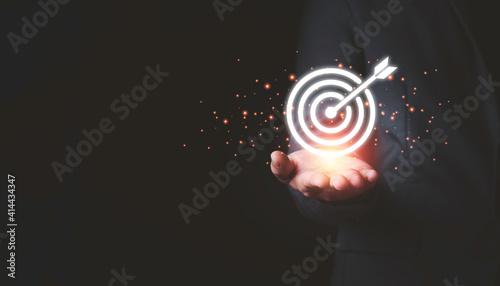 Businessman holding virtual  dartboard and arrow with copy space for setup business objective target concept.