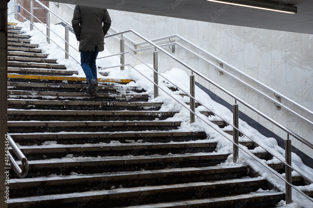 Man climbs the snow-covered stairs of the underpass.