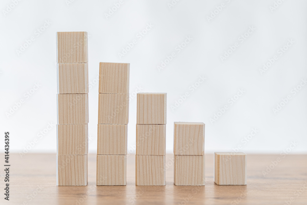 Businessman hand arranging wooden blocks in an upward stepping stair.  Concept for growth, success, investment strategy.