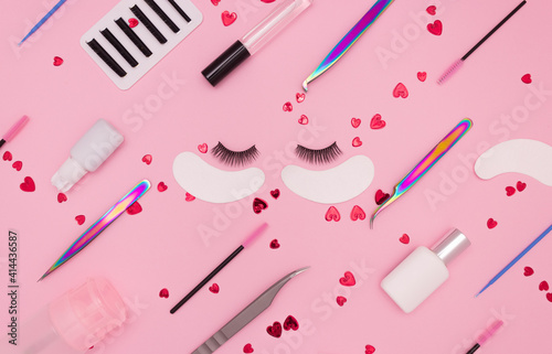 Foto Eyelash extension tools, artificial eyelashes and red hearts on a pink background