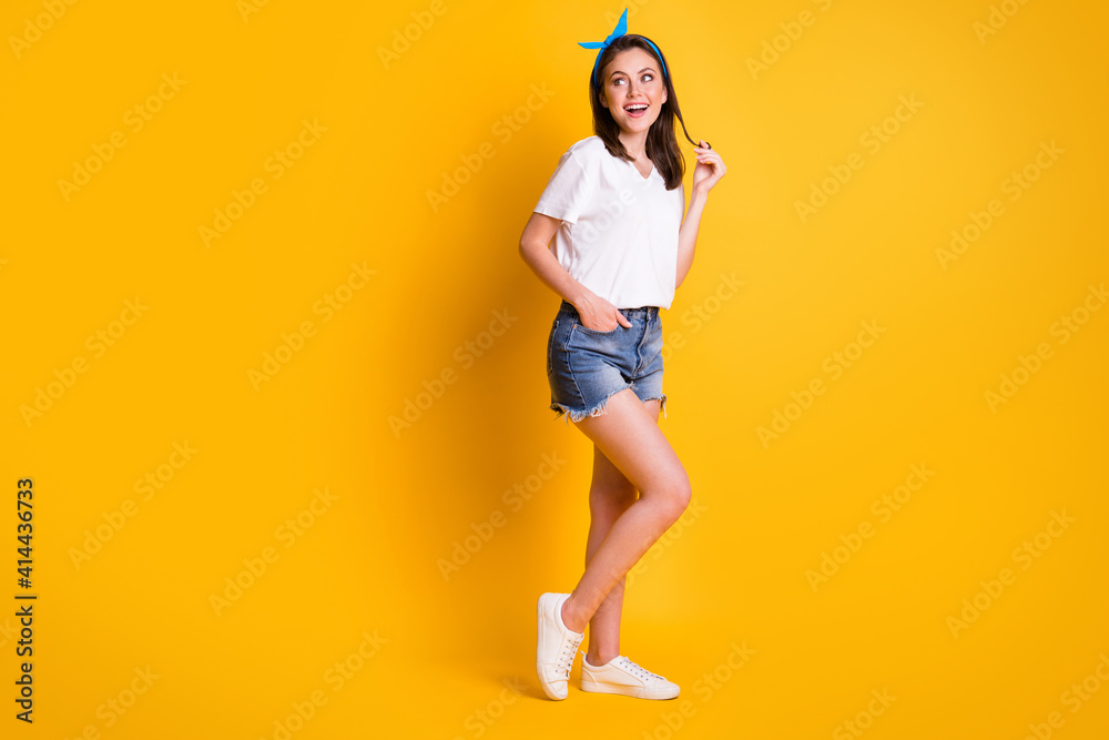 Full length photo of girl play curl look empty space wear blue headband white t-shirt mini shorts footwear isolated yellow color background Full length photo of girl play curl look empty space wear blue headband white t-shirt mini shorts footwear isolated yellow color background