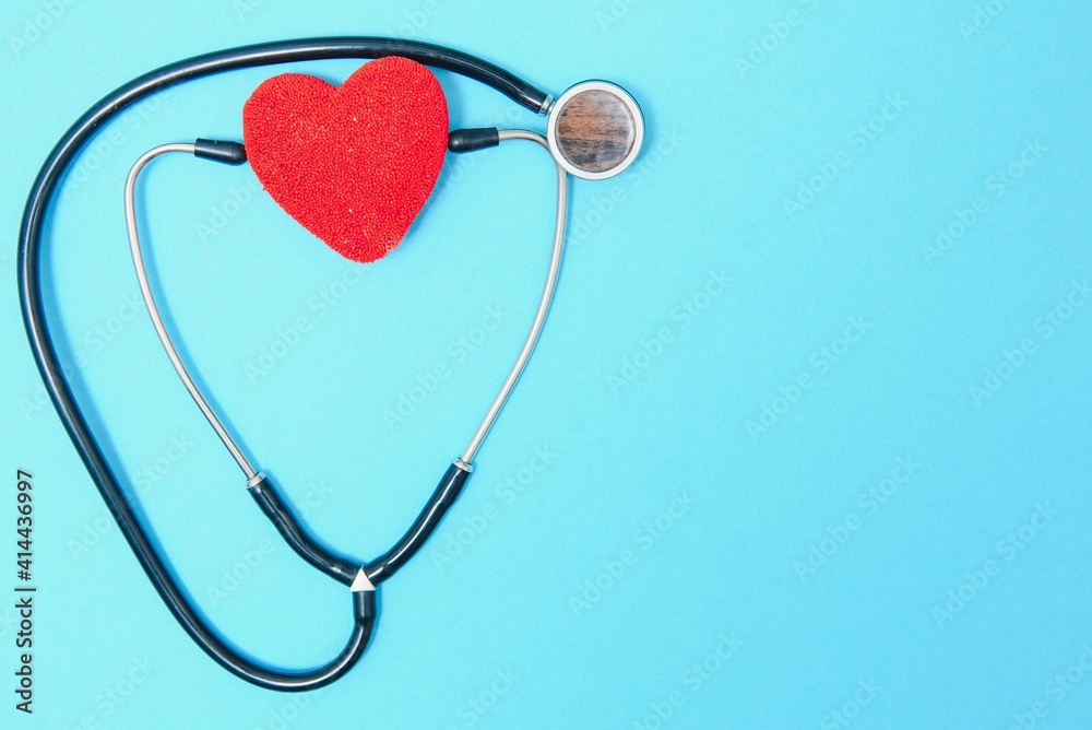 Close-up of a heart and a stethoscope on a blue background, top view. Global health care concept. caring for heart health. treatment with tablets and ampoules Close-up of a heart and a stethoscope on a blue background, top view. Global health care concept. caring for heart health. treatment with tablets and ampoules