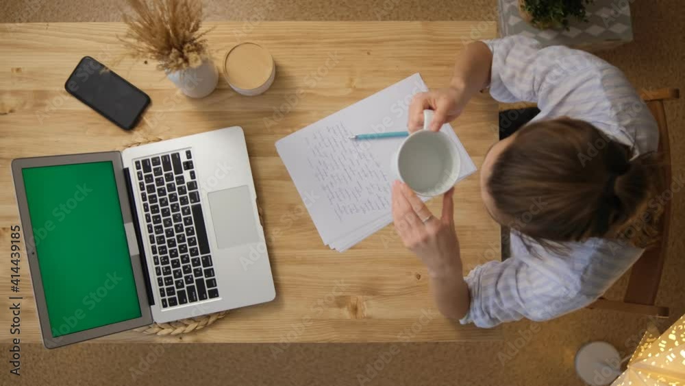 Remote work, get a drink of water. The woman works remotely and is trained. I took a break to drink some water. holding a cup of water in her hands in the morning. Top view. Remote work, get a drink of water. The woman works remotely and is trained. I took a break to drink some water. holding a cup of water in her hands in the morning. Top view.