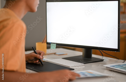 Graphic designer working on digital board with mockup computer monitor blank screen.