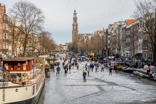 People ice scating on frozen canal in city center of Amsterdam photo