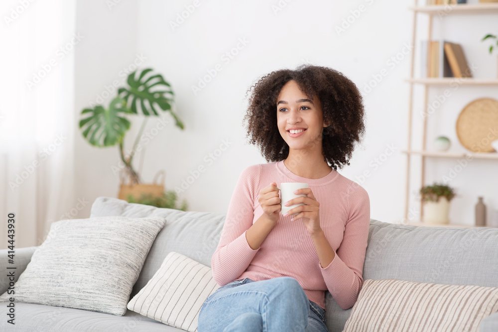 Calm happy woman relaxing and drinking hot drink at home during free time at lockdown Calm happy woman relaxing and drinking hot drink at home during free time at lockdown