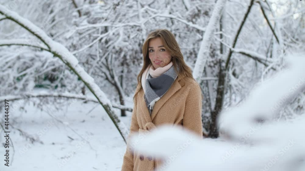 a beautiful girl stands in a fabulous snow-covered park among the icy branches of trees, looks at the camera and smiles mysteriously surrounded by snow a beautiful girl stands in a fabulous snow-covered park among the icy branches of trees, looks at the camera and smiles mysteriously surrounded by snow