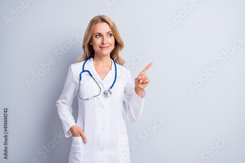 Obraz na plátně Photo of mature charming lovely positive medic woman point finger copyspace isol