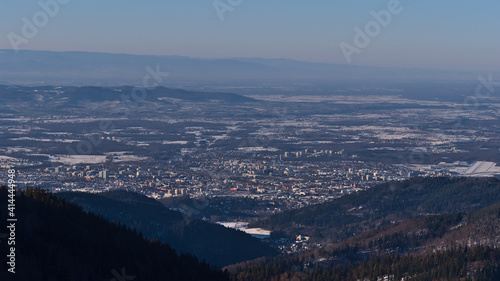 Beautiful aerial view of city Freiburg im Breisgau, Kaiserstuhl hills and Vosges mountain range on horizon in winter with snow-covered landscape viewed from Schauinsland peak, Black Forest, Germany.