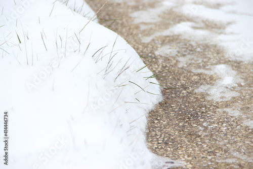 neige sur le bord d'une allée avec herbe apparente photo