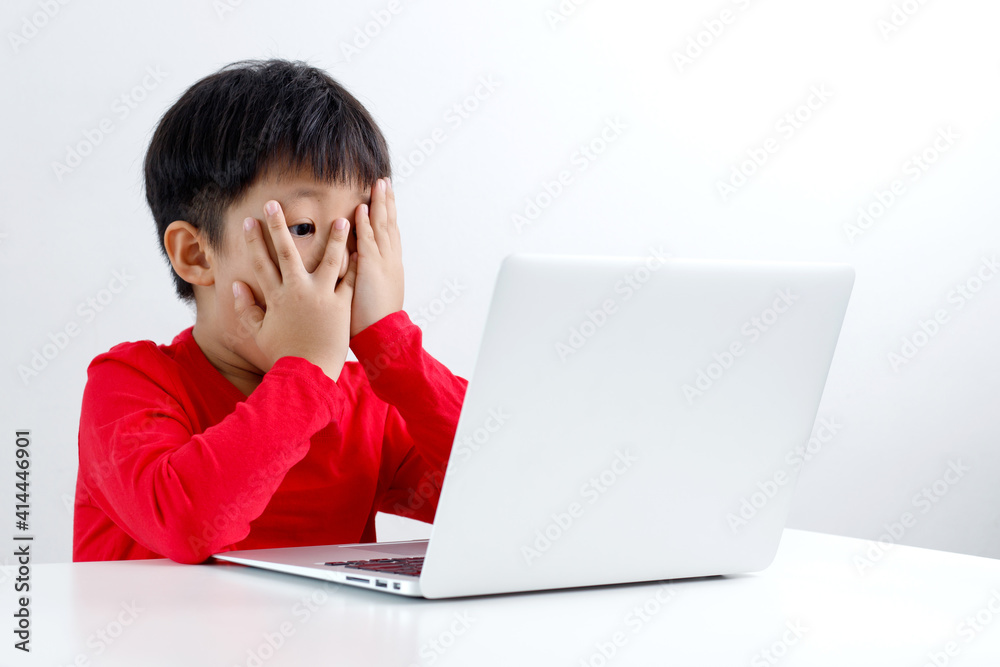 Shocked and surprised little Asian boy peeking on the internet with laptop computer isolated on white background. Shocked and surprised little Asian boy peeking on the internet with laptop computer isolated on white background.