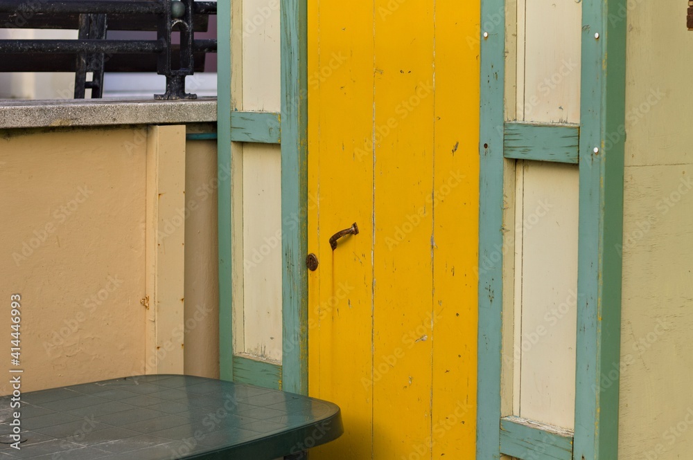 A yellow wooden door of a white and green beach hut (Pesaro, Italy, Europe)