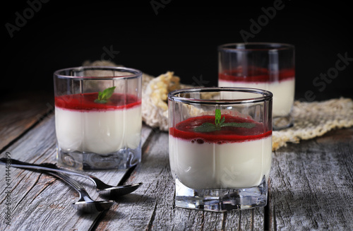 Panna cotta in a glass with a mint leaf. Dessert on a wooden table