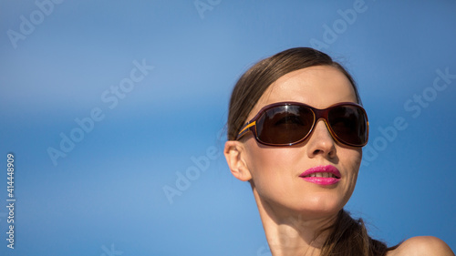 Young woman with sunglasses on a blue sky background