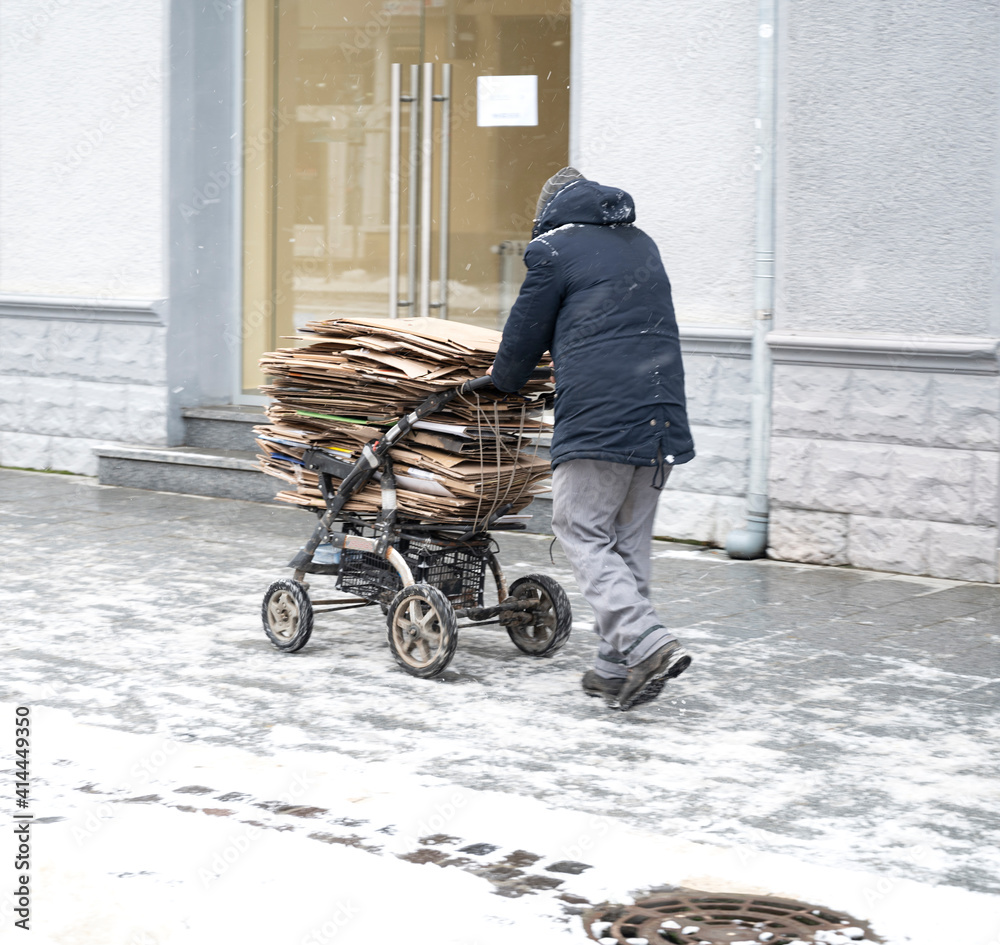 Poor man pulling a cart with cardboard in the city