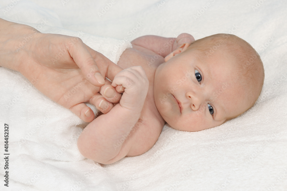 Baby lying on a white blanket and his mother's hand Baby lying on a white blanket and his mother's hand