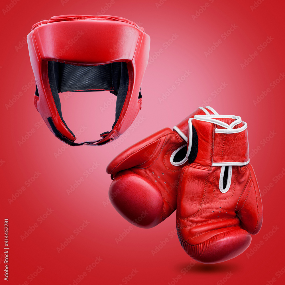 Red boxing helmet and boxing gloves on a red background.