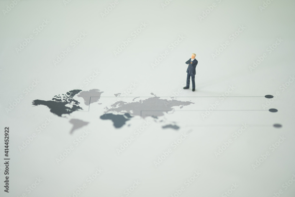Miniature businessman leader in suit standing on map globe and looking goal achievement. Miniature businessman leader in suit standing on map globe and looking goal achievement.