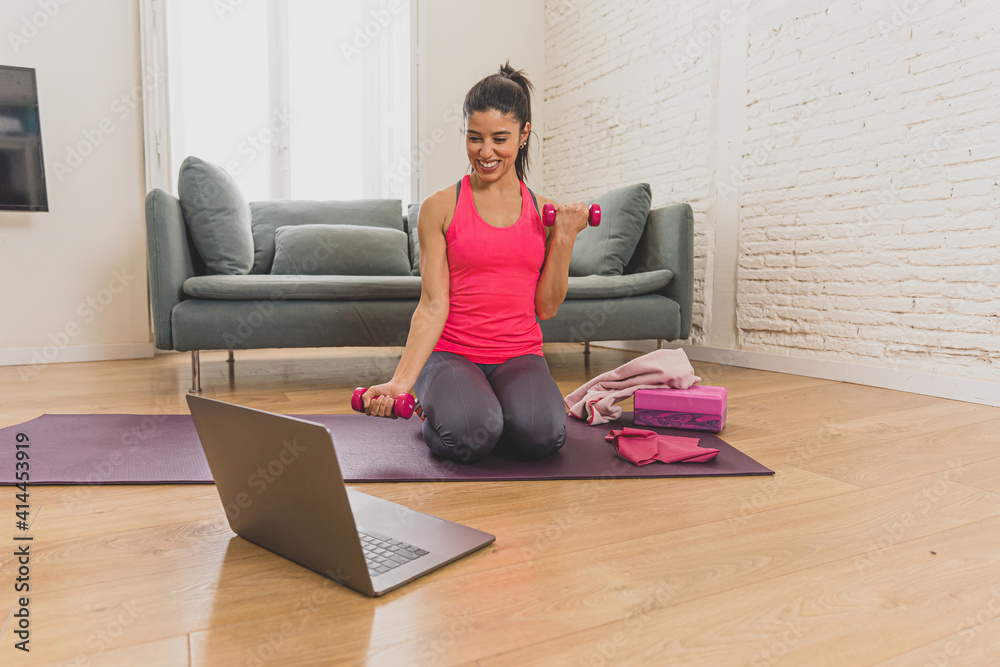 Attractive woman on laptop in virtual online fitness class working out at home