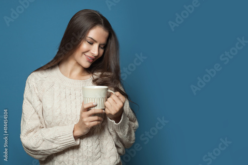 Beautiful casual woman drinking coffee on blue background