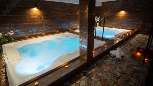 Private whirlpool in a wellness center. Indoor jacuzzi with bubbles. Candles around a whirlpool with blue water. 