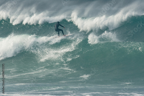 Surfer Carving and performing tricks on huge blue waves in Newquay, Cornwall - Southwest England © Theo