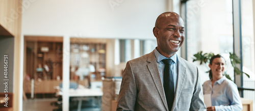 African American businessman laughing while walking through a modern office