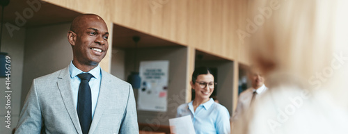 Fotografie Smiling African American businessman walking with colleagues in an office