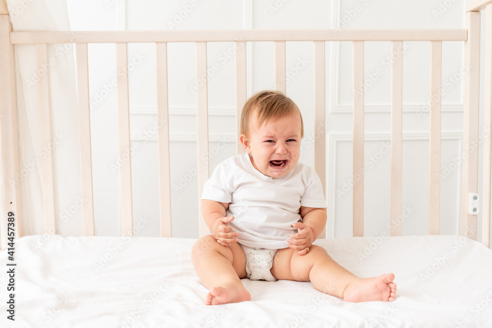 a baby cries in the crib, a boy of 6 months screams or cries at home a baby cries in the crib, a boy of 6 months screams or cries at home