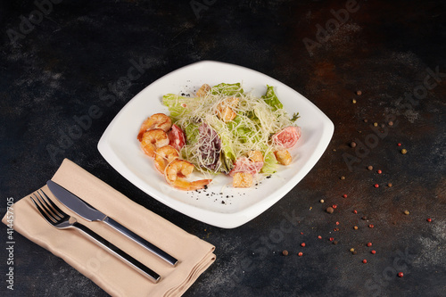 Caesar salad with seafood and shrimp, background dark