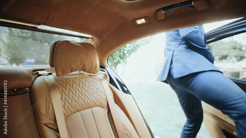 Portrait of successful businessman talking on phone in salon of modern car.