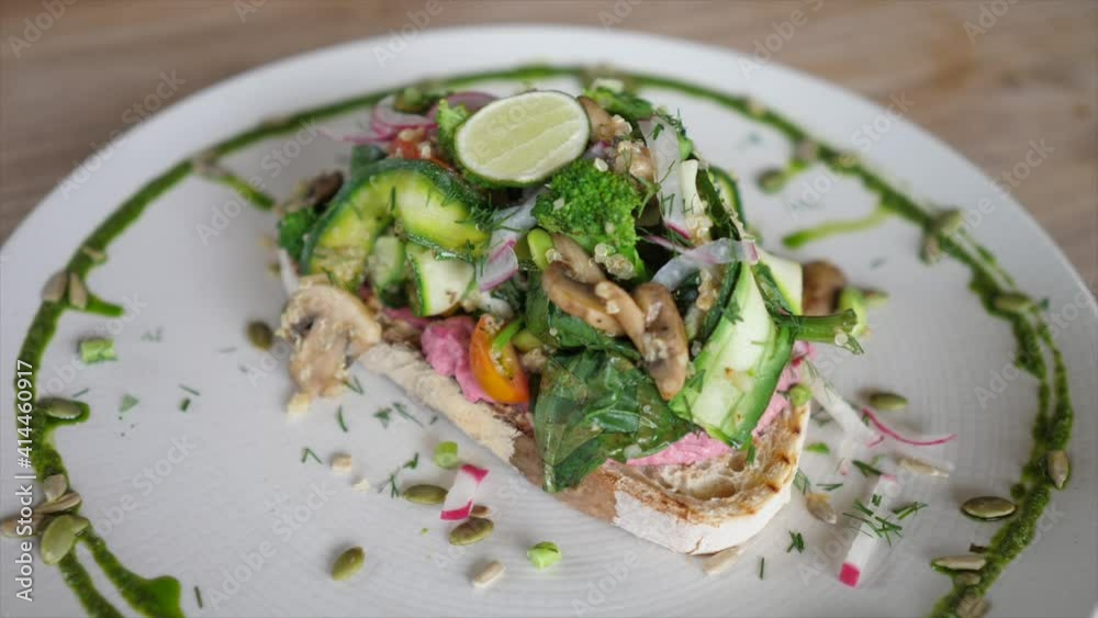 Top view of plate with amazing vegan sandwich topped with tons of vegetables is being served on the wooden table Top view of plate with amazing vegan sandwich topped with tons of vegetables is being served on the wooden table
