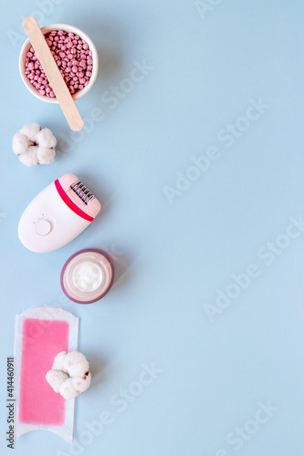 Cosmetics set for epilation with epilator and wax strips and flowers. Top view