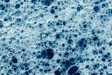Soap bubbles on a background of blue water as a texture. Top view. Copy, empty space for text